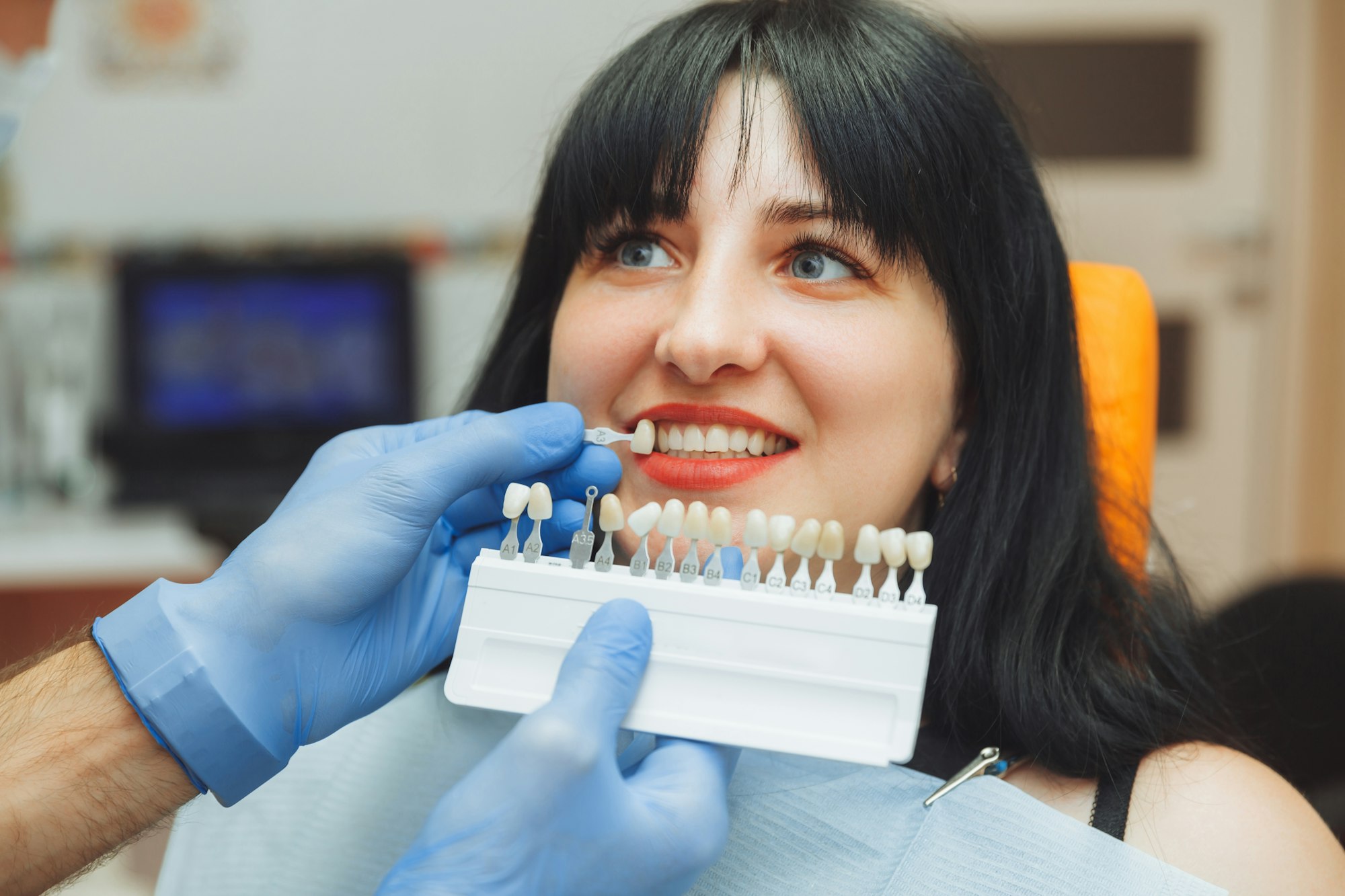 Dentist selecting enamel color for veneers on a woman at Cosmetic Dental Associates in San Antonio, showcasing precision and expertise in cosmetic dentistry.